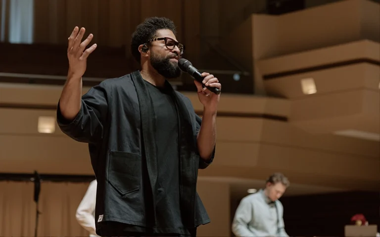 A worship leader holding a microphone and leading worship during the Good Friday service at New City Church in Naperville.