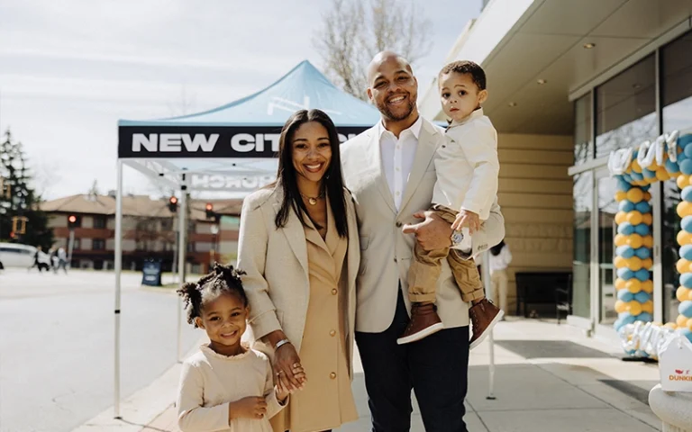 A young family with two children smiling in front of New City Church in Naperville on Easter Sunday.